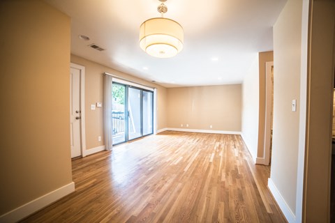 an empty living room with wood floors and a sliding glass door