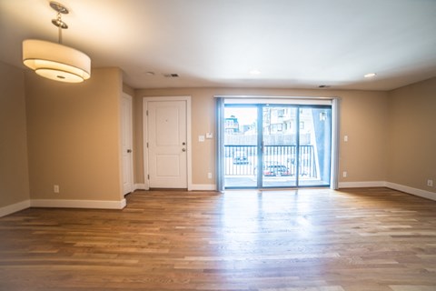 an empty living room with wood floors and a sliding glass door