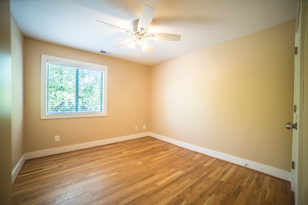 an empty living room with a ceiling fan and a window
