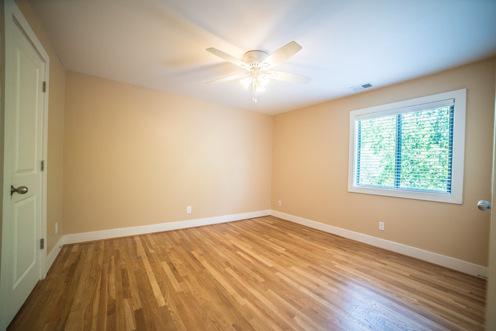 an empty living room with wood floors and a ceiling fan