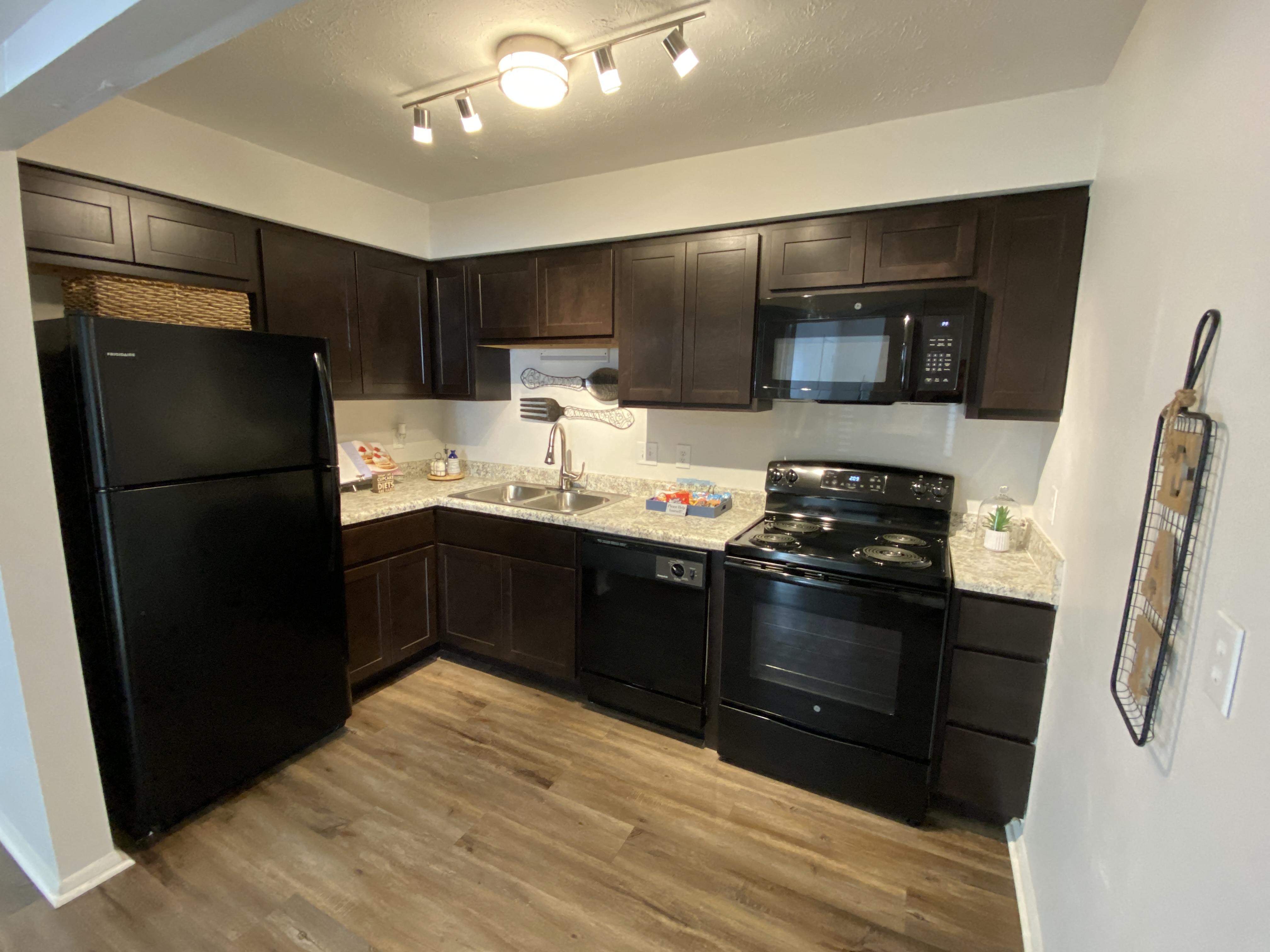 A kitchen with black appliances and brown cabinets.