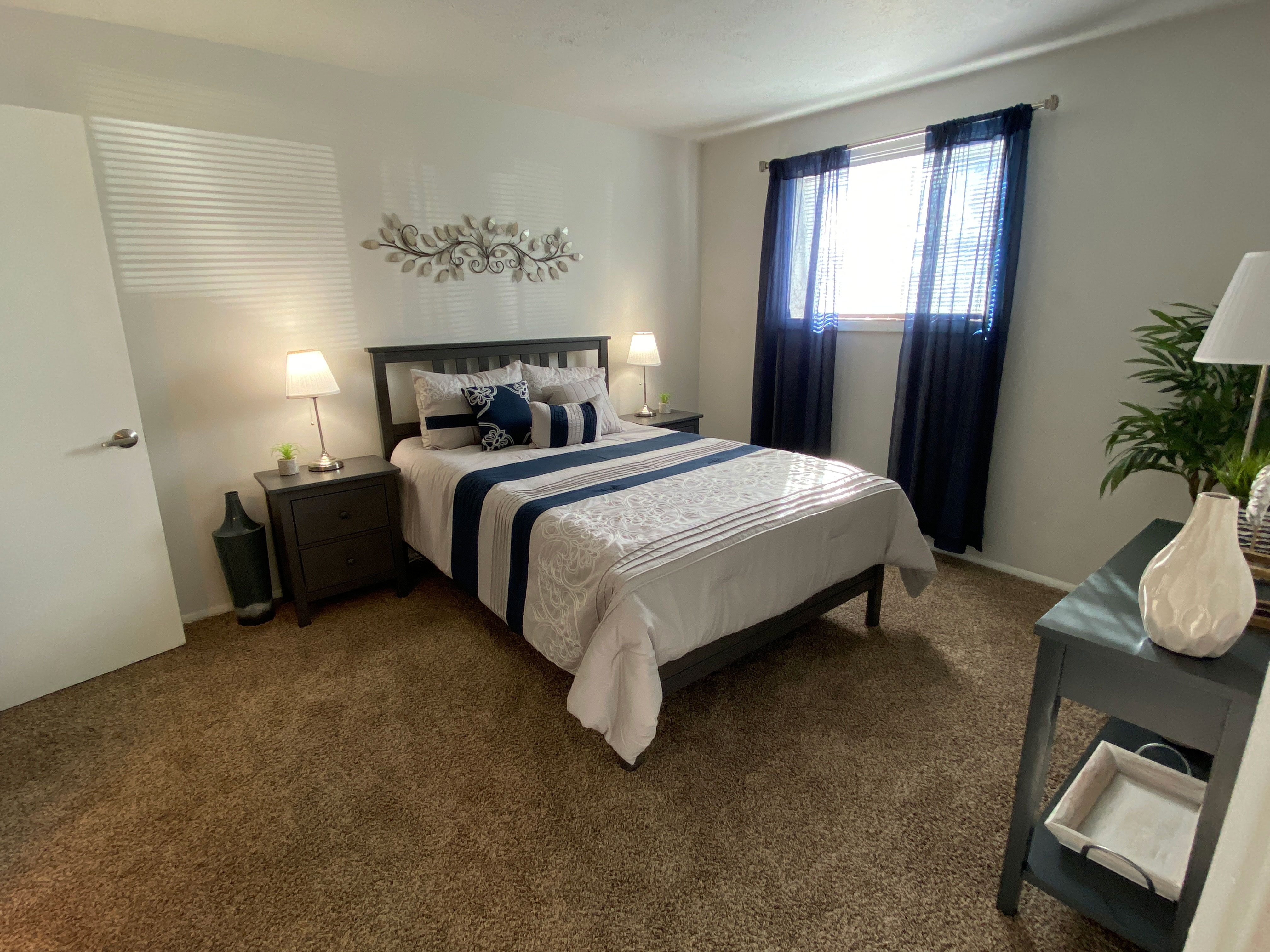 A bedroom with a large bed and a nightstand with a lamp.