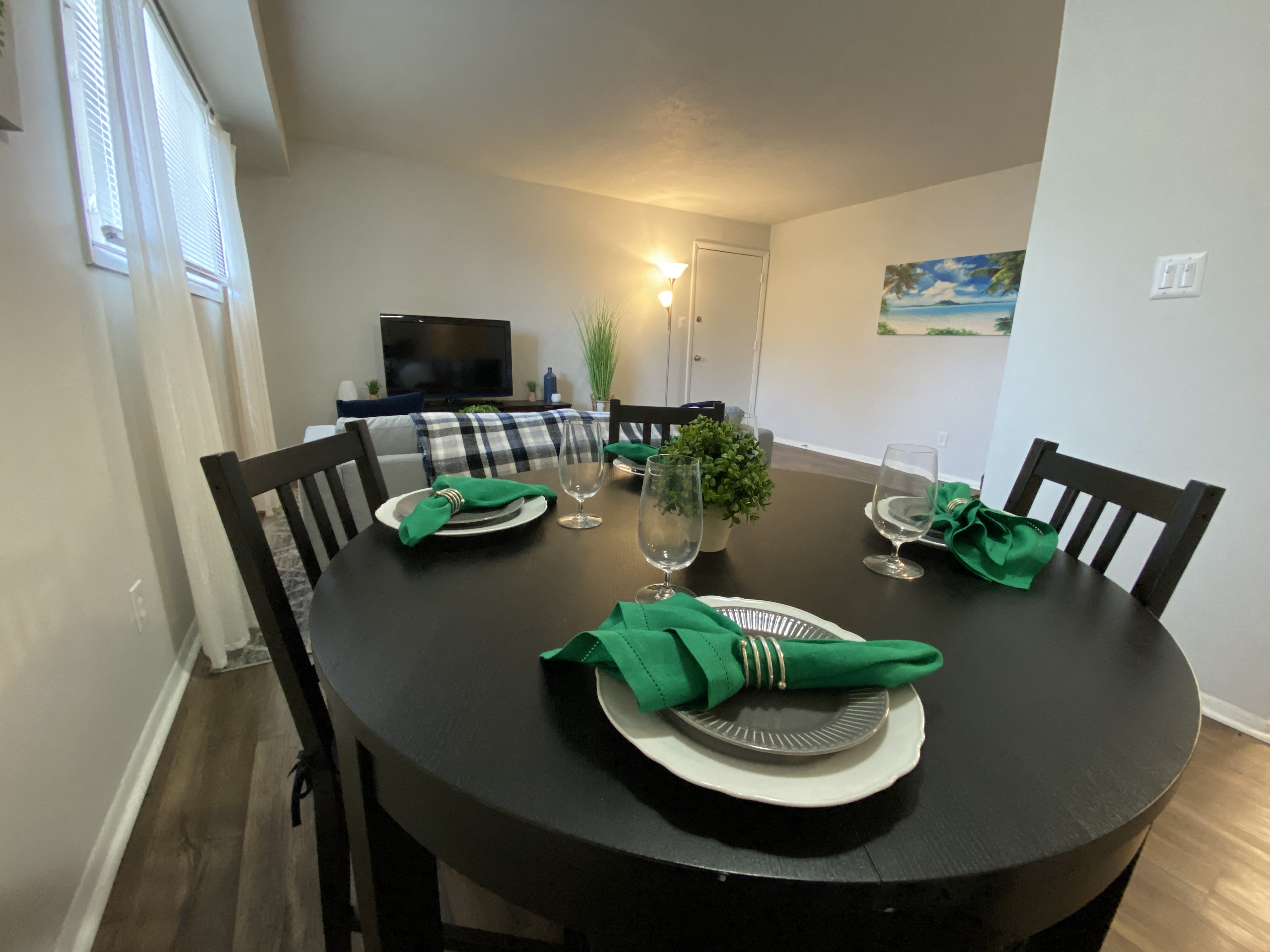 A black dining table set with green napkins and plates.