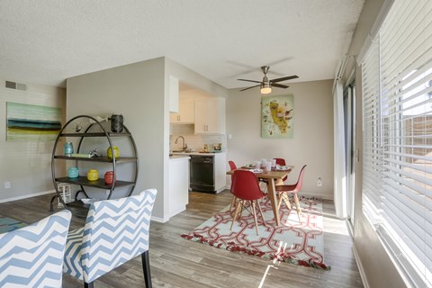A dining room with a table set for two and a kitchen in the background.