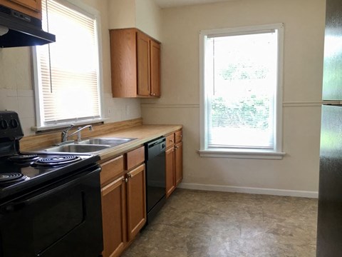A kitchen with black appliances and wooden cabinets.