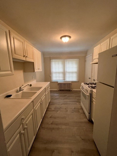 a white kitchen with a sink and a refrigerator