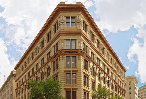 A large brown building with many windows and a triangular top.