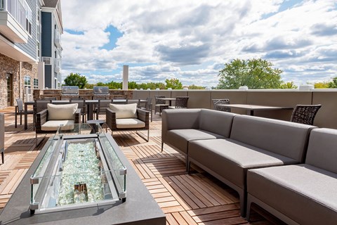 a rooftop patio with couches and tables and a glass fireplace
