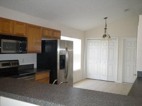 A kitchen with a black refrigerator and wooden cabinets.