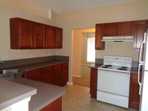 A kitchen with a white stove and wooden cabinets.