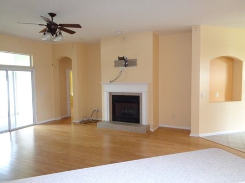an empty living room with a fireplace and a ceiling fan
