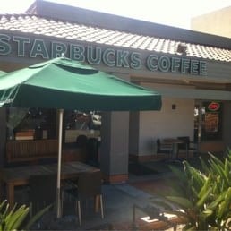 A green umbrella is in front of a Starbucks Coffee.