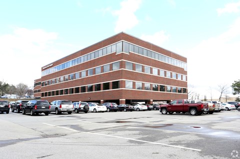 A parking lot with cars and a red truck in front of a brick building.