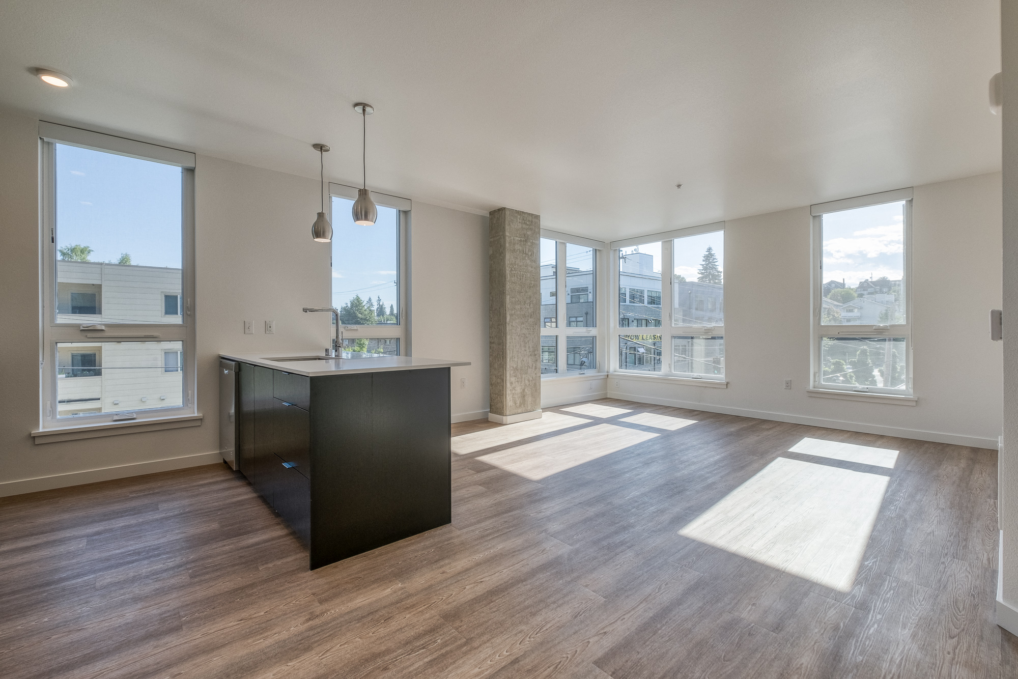 an open living room with a kitchen and large windows