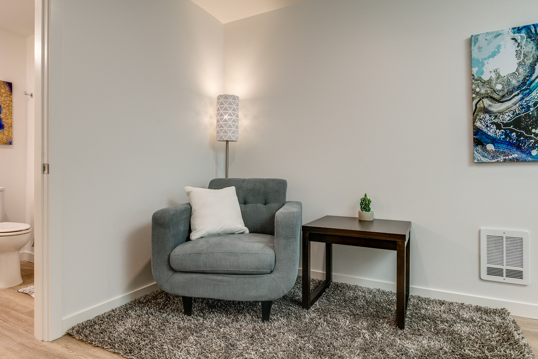 a living room with a chair and a table with a lamp
