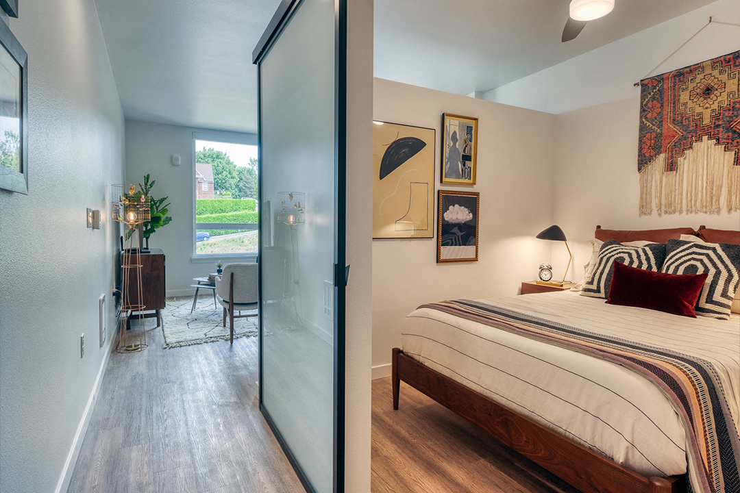 a bedroom with a bed and a sliding glass door to a living room
