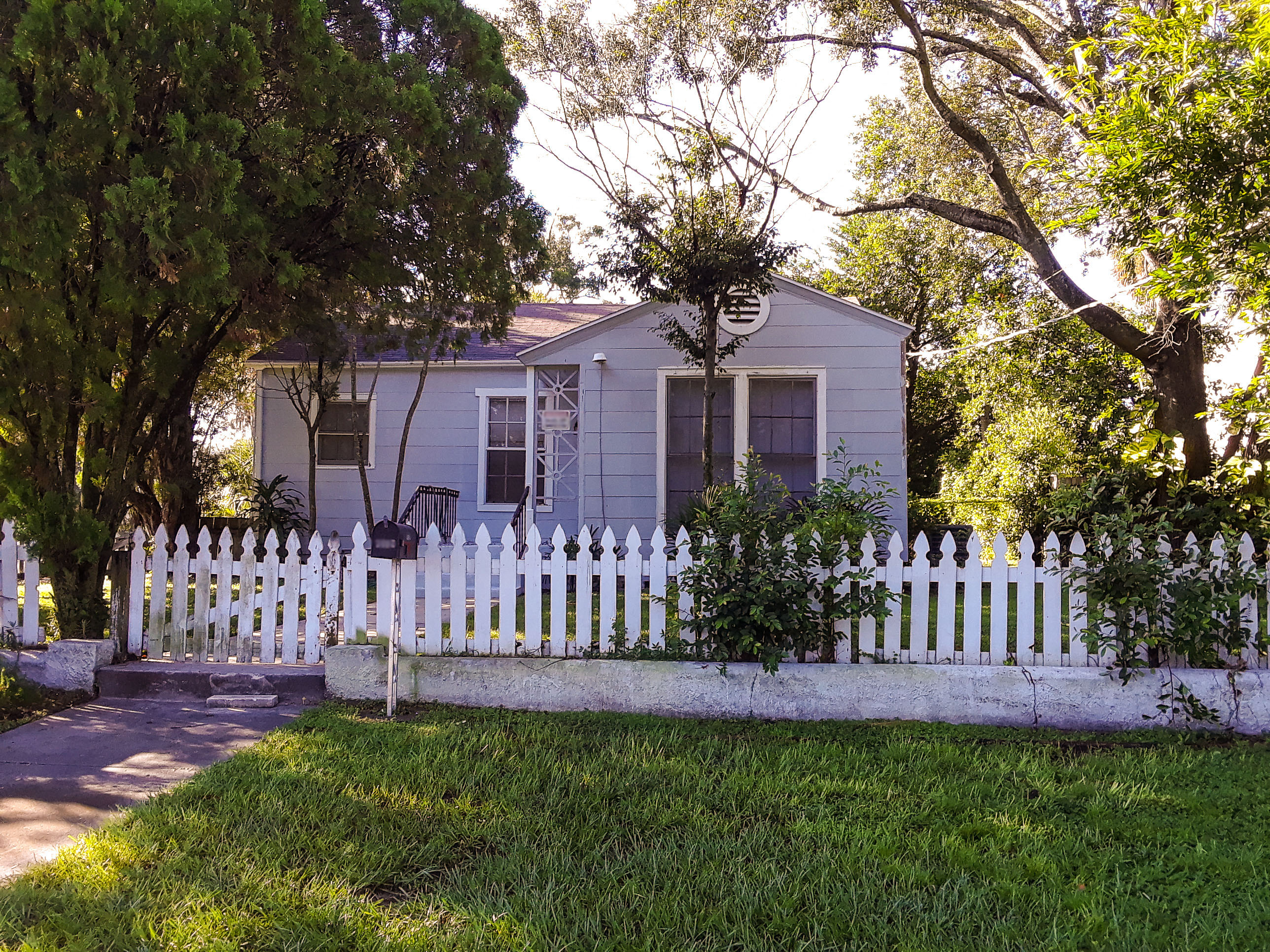 A house with a white picket fence is surrounded by trees.
