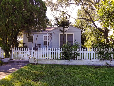 A house with a white picket fence is surrounded by trees.