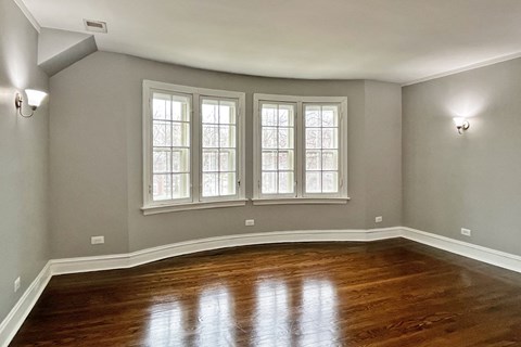 A room with wooden floors and three windows.