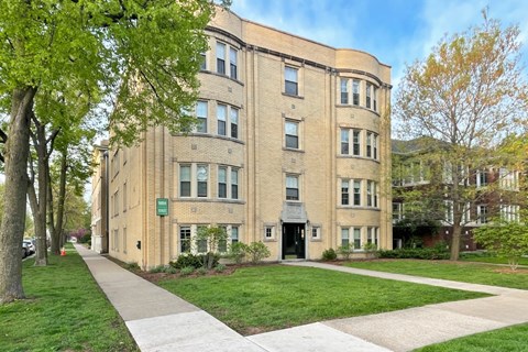 A large tan building with a green sign on the front.