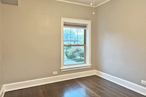A room with a window and wooden flooring.