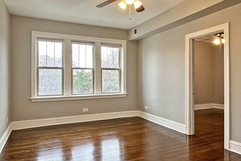 A room with a ceiling fan and a large window.