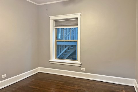 A room with a window showing a view of a building outside.