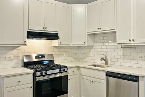 A kitchen with white cabinets and a black stove top.