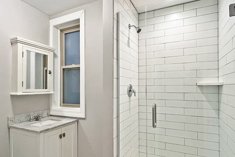 A white bathroom with a sink and a shower.