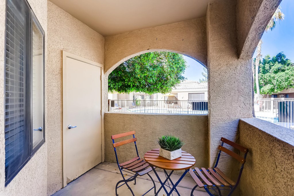 a patio with two chairs and a table with a potted plant