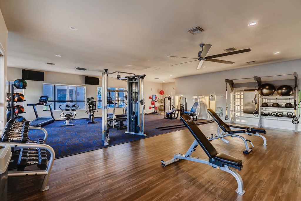 a home gym with exercise equipment and a ceiling fan