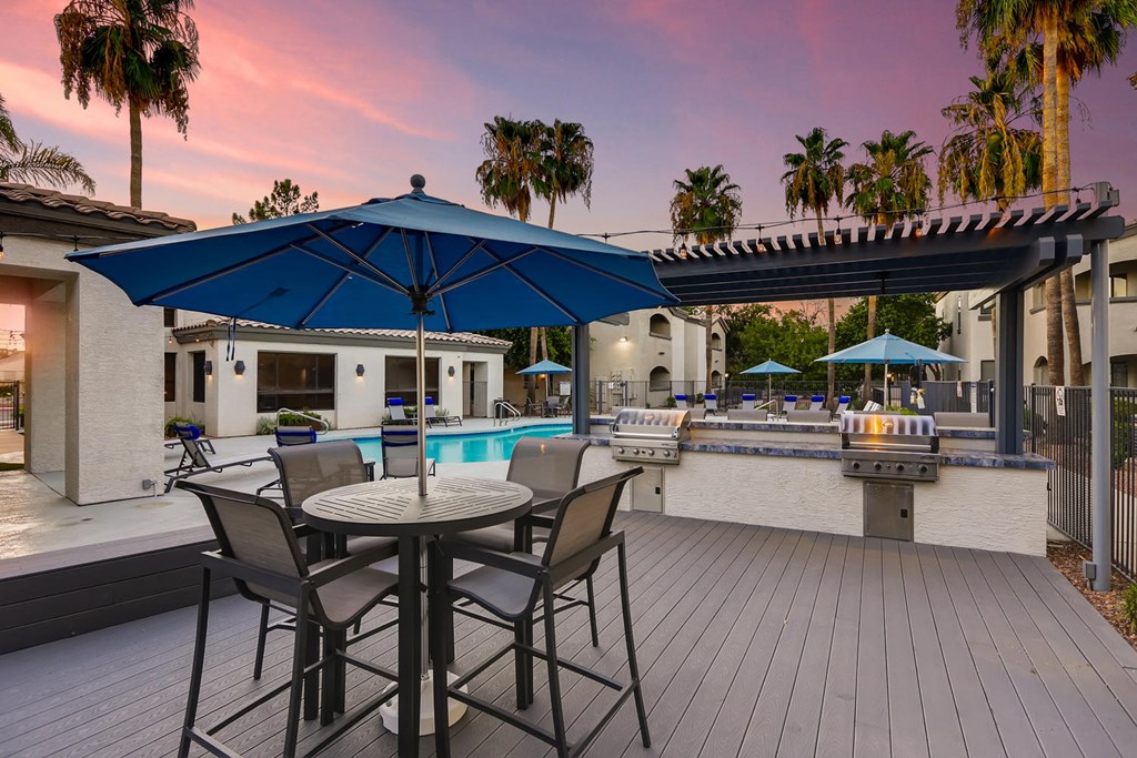 a patio with tables and umbrellas and a swimming pool