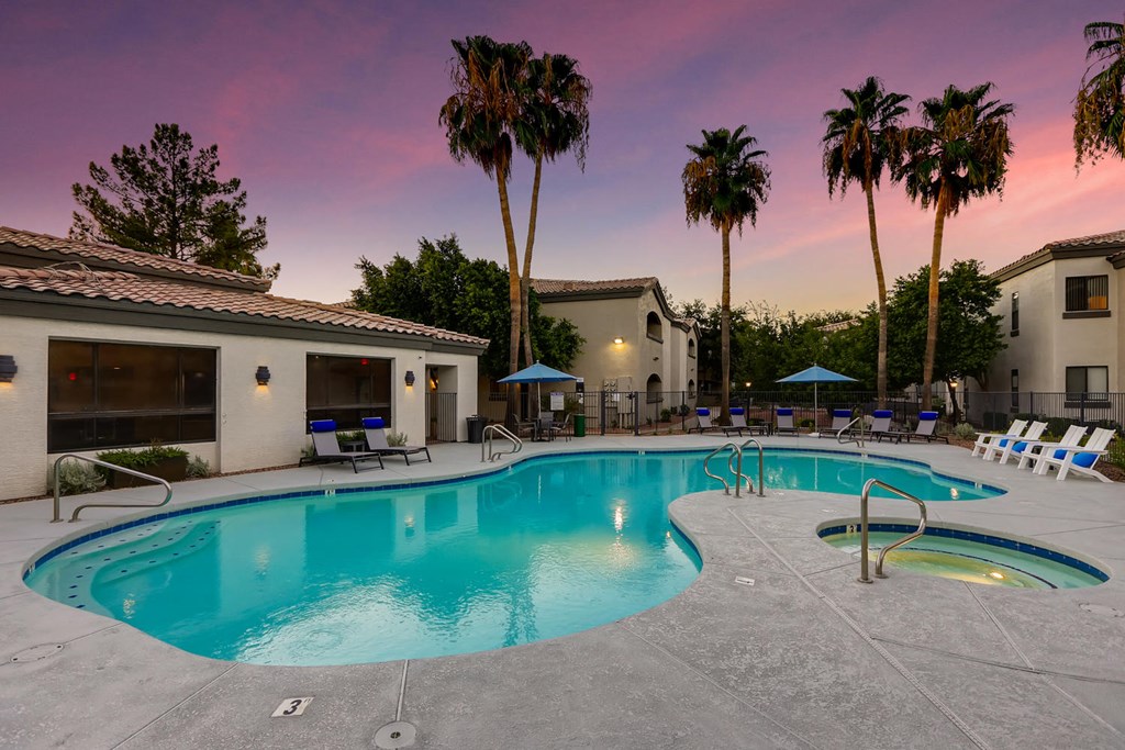 a resort style swimming pool with chairs and palm trees