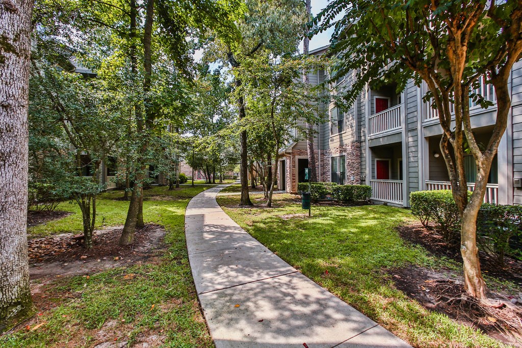 a sidewalk in front of an apartment building with trees