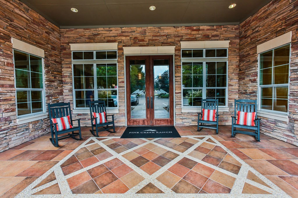 the front porch of the house has rocking chairs and a rug