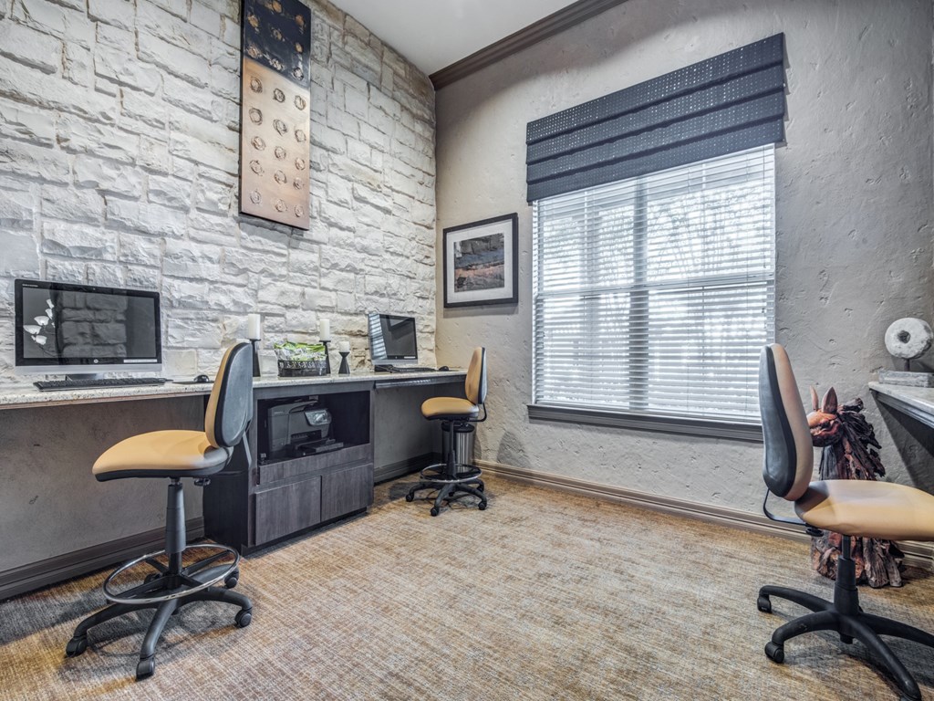 an office with two chairs and a desk with a computer and a window