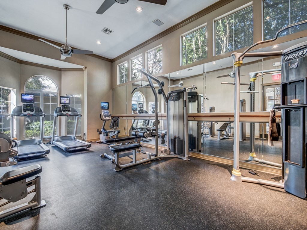 a gym with weights and cardio equipment and windows