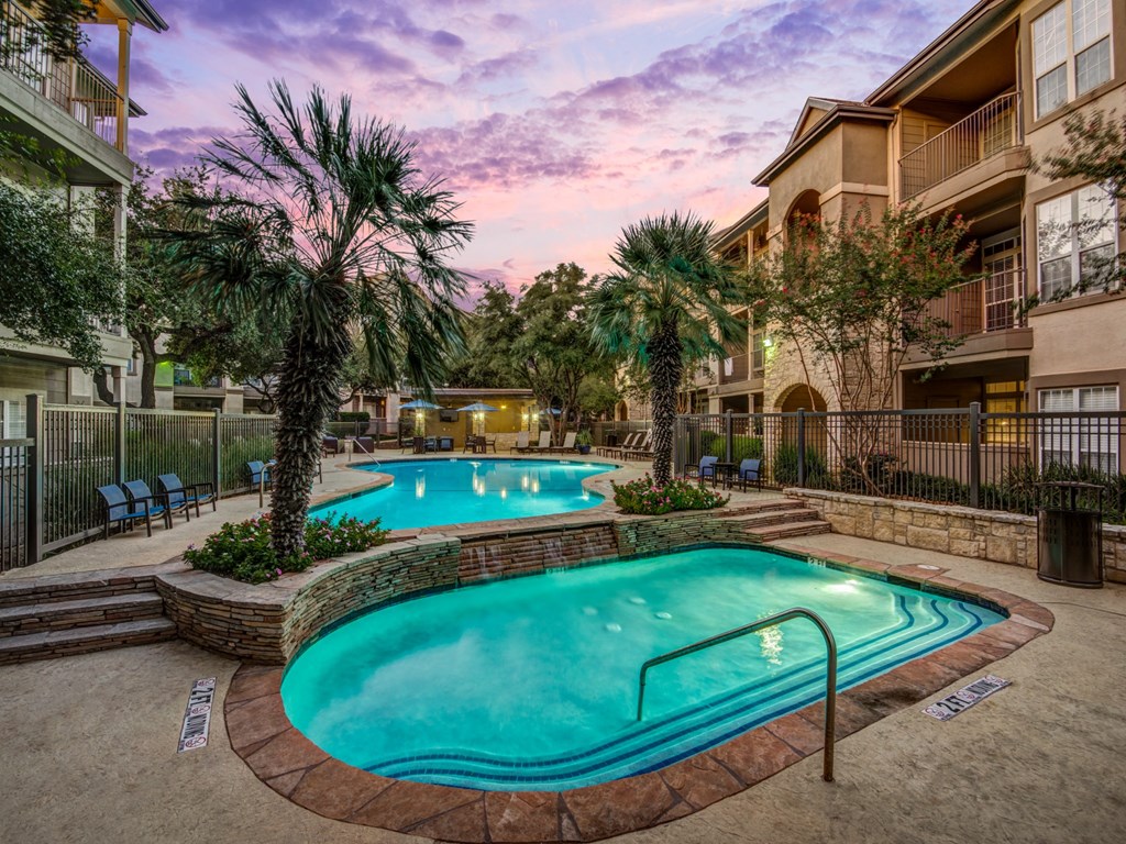 a large swimming pool with palm trees in front of an apartment building