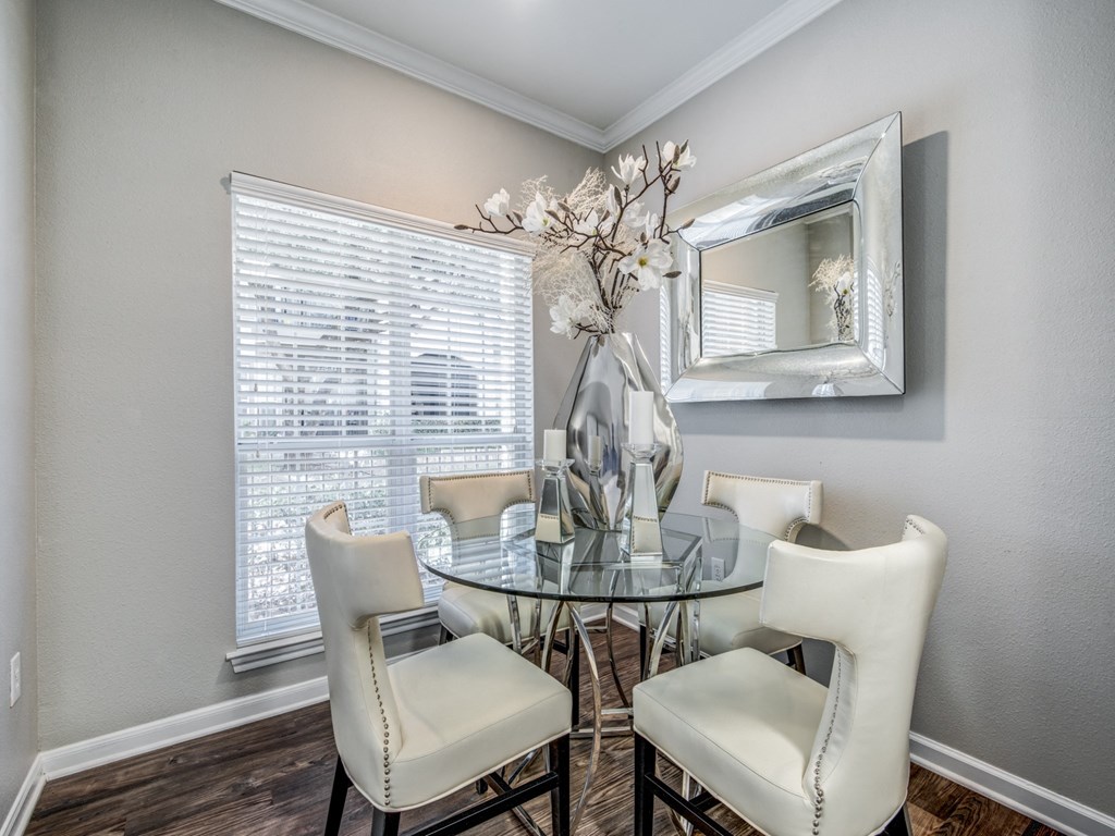 a dining room with a glass table and chairs and a window