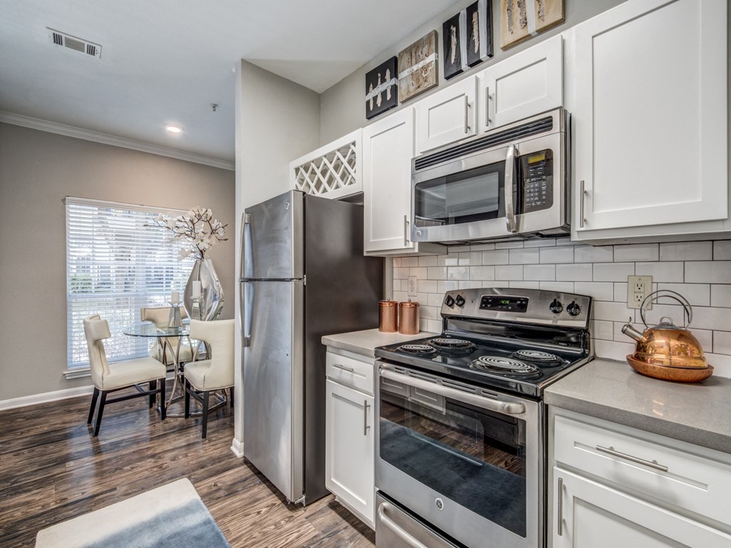 an open kitchen with stainless steel appliances and white cabinets