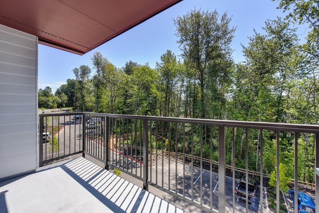 Gated Apartment Patio Exterior looking over Parking lot with Cars and Trees