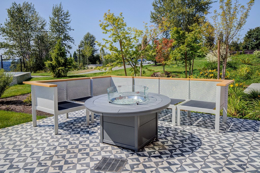 Outside Community Patio with Seats, Fireplace, Marbel Inspired Ground, and Trees