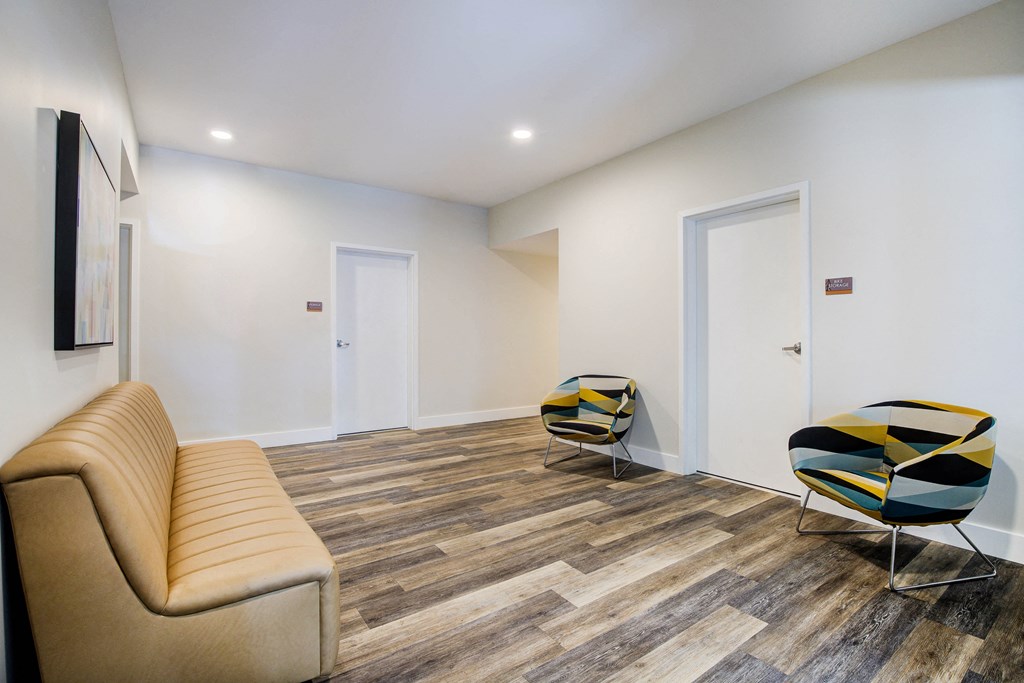 Lobby with Tan Sofa, Hardwood Inspired Floor, White Walls and Yellow/Dark Blue Chairs