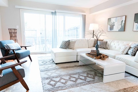 a living room with white furniture and a large rug