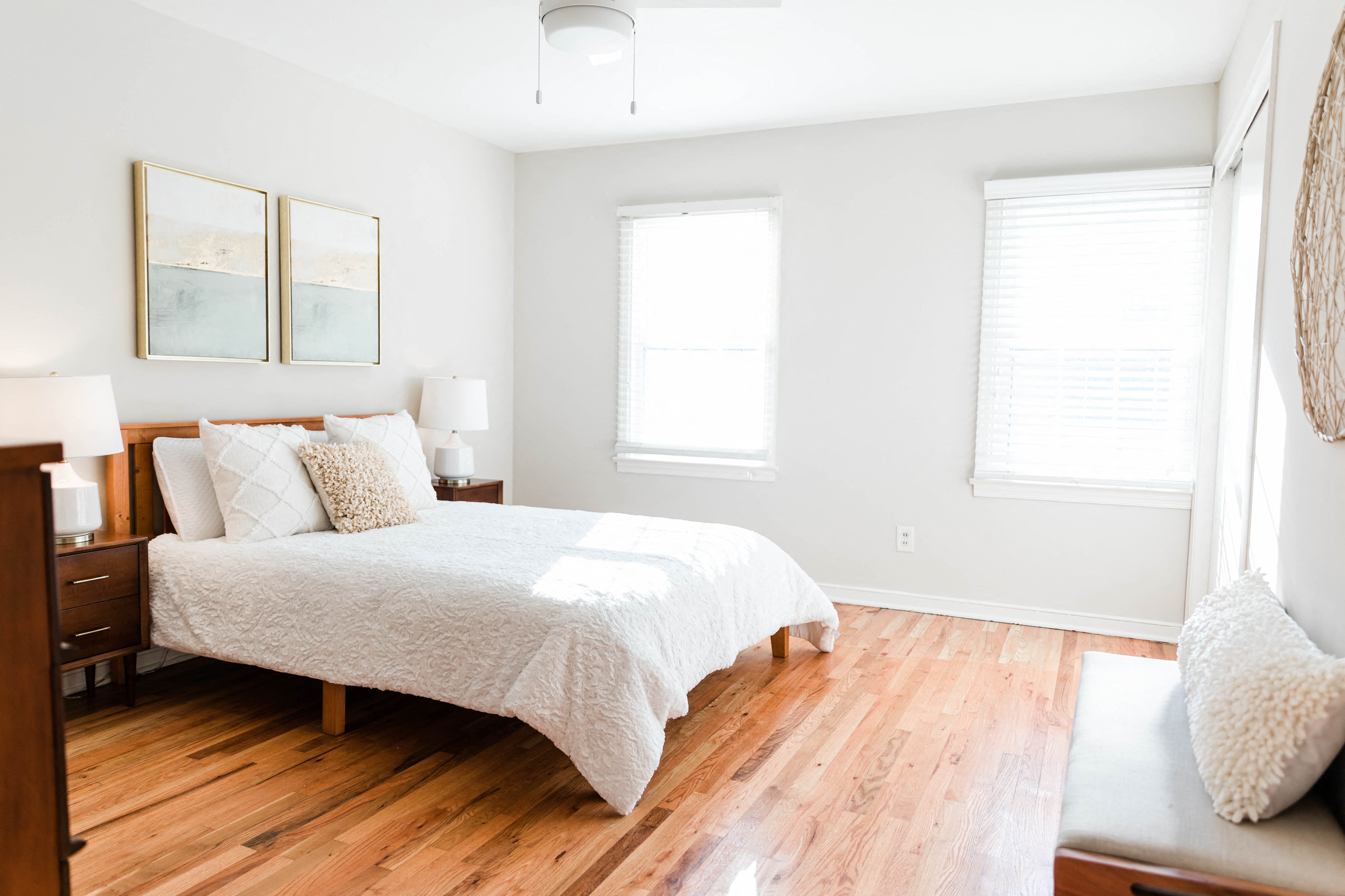 a bedroom with a bed and two windows and a wooden floor