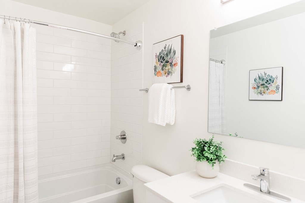 a white bathroom with a tub and a sink and a mirror