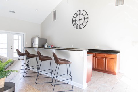 a kitchen with a bar with three stools and a clock on the wall