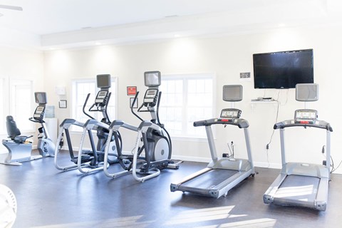 a row of exercise bikes in a gym with a tv