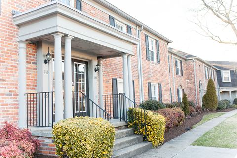 the front of a brick house with white columns and a porch