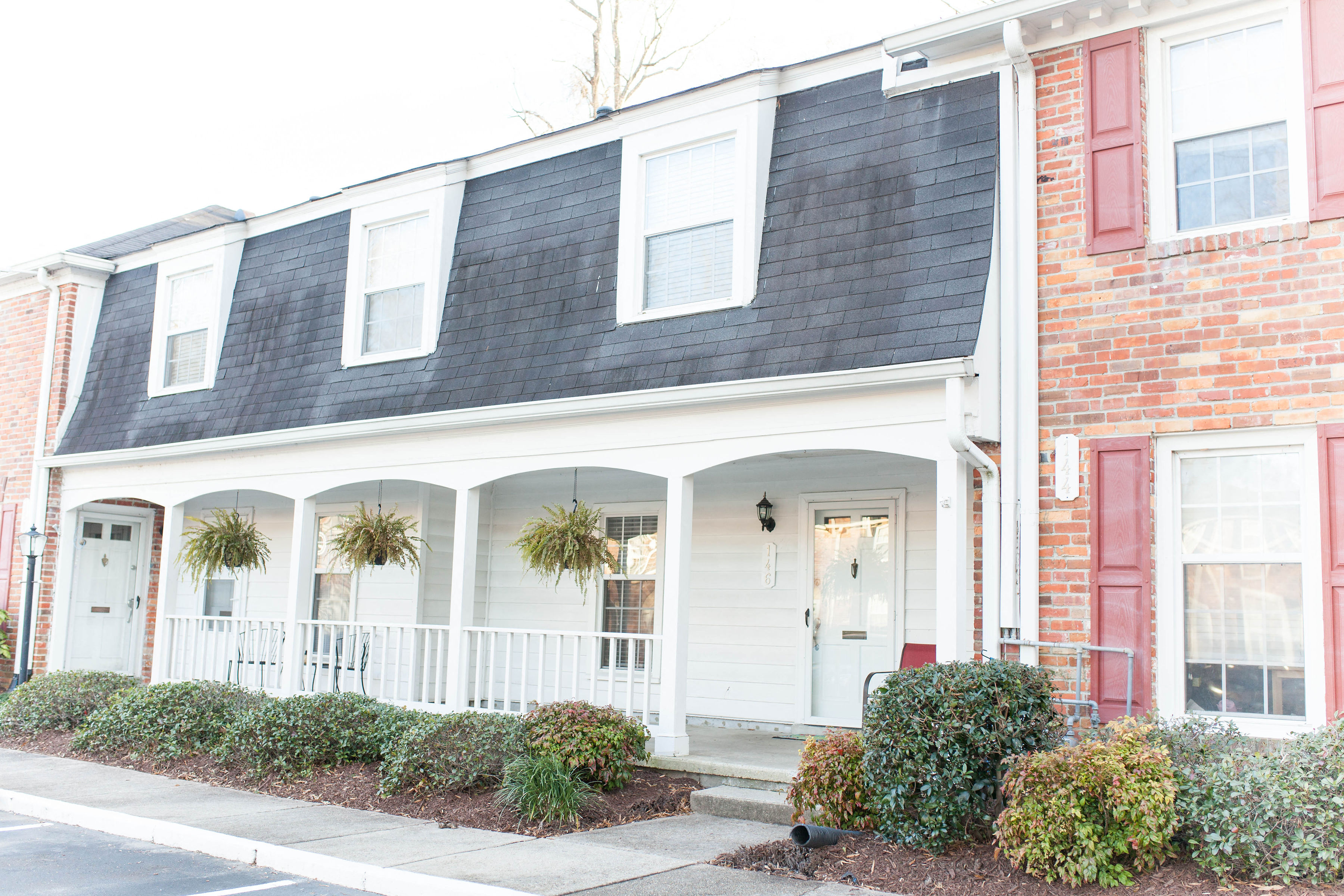 the front porch of a brick house with a porch swing